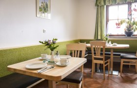 Naturpension Artner, © Waldviertel Tourismus, Robert Herbst Gemütlicher Frühstücksraum mit Holztischen, grünen Bänken und Blumen auf dem Tisch.