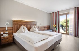 Wohlfühlzimmer, © Gesundheitshotel Moorbad Bad Großpertholz Ein gemütliches Hotelzimmer mit Doppelbett, Holzmöbeln und Balkon mit Blick ins Grüne.