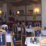 Ein gem&uuml;tliches Restaurant mit Holzm&ouml;beln, gedeckten Tischen und Wanddekorationen.