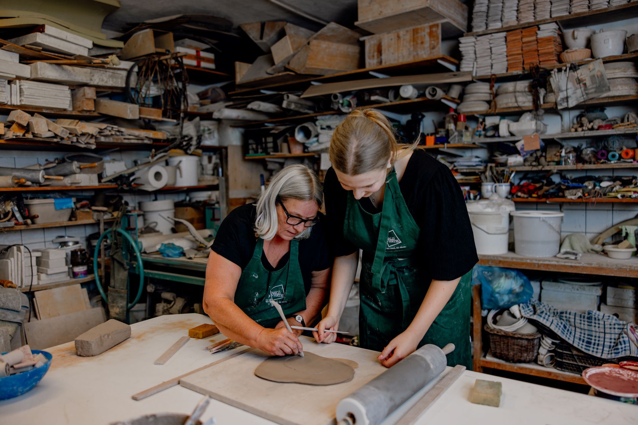 Zwei Frauen arbeiten in einer Keramikwerkstatt an einem Tonstück.