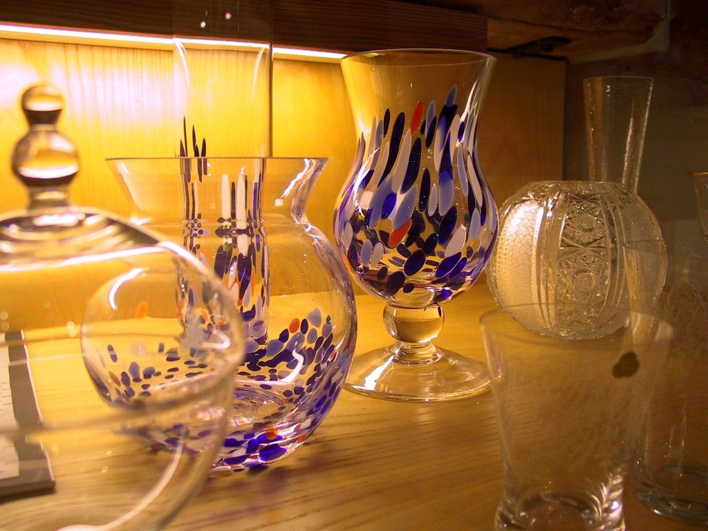 Verschiedene bunte Glasvasen auf einem Holzregal.