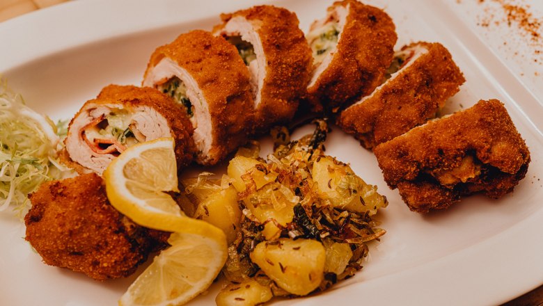 Gef&uuml;lltes gebackenes Putenfilet mit Kartoffelbeilage und Zitronenscheiben auf einem wei&szlig;en Teller.