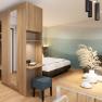 Modern eingerichtetes Apartment mit Holzm&ouml;beln, einem Bett, einem kleinen Tisch mit Stuhl und dekorativen Pflanzen.