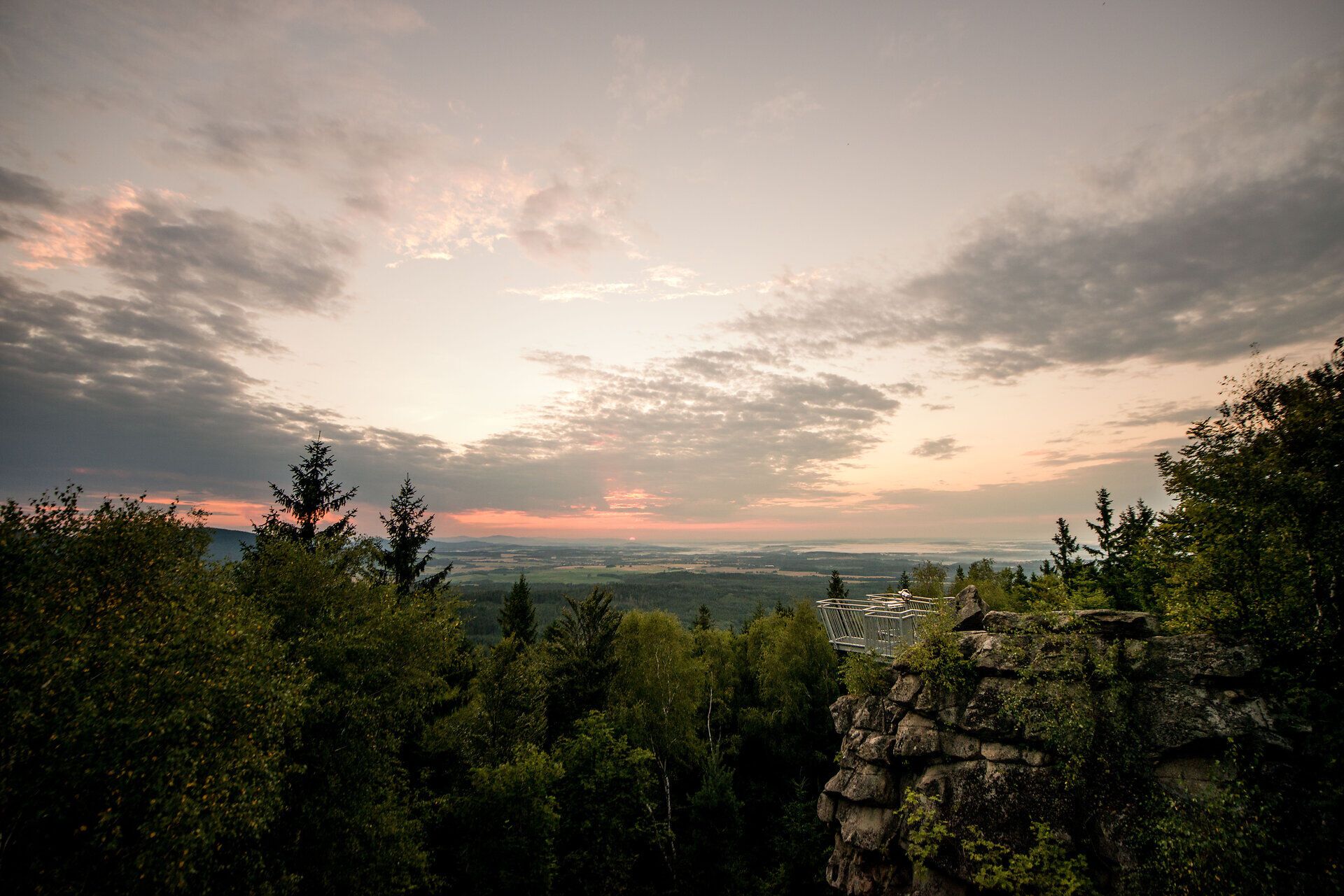 Die sanften Hügel und dichten Wälder laden zu unvergesslichen Wanderungen ein, während die untergehende Sonne den Himmel in warmen Farben erstrahlen lässt. Hier, inmitten der Natur, entfaltet sich eine friedliche Atmosphäre, die zum Verweilen und Entspannen einlädt.