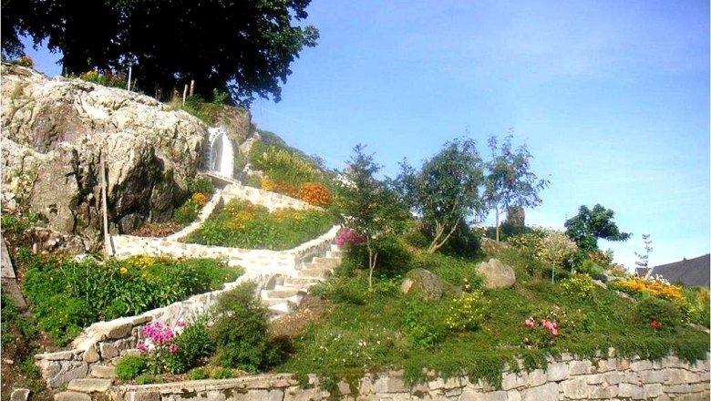 Steingarten mit Blumen und Treppe, umgeben von B&auml;umen.