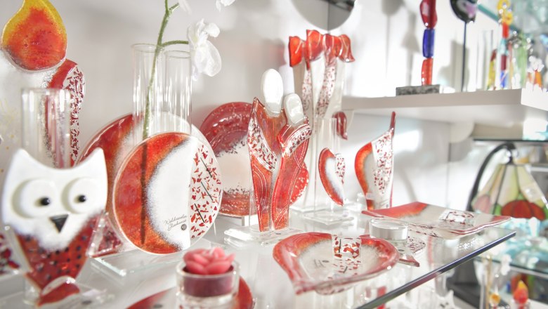 Glasdekorationen in Rot und Wei&szlig; auf einem Regal.