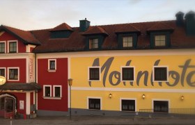 Fassade des Bergwirt Schrammel & Mohnhotel mit rotem und gelbem Anstrich.