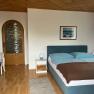 Schlafzimmer mit Doppelbett, Kommode und Holzt&uuml;r.
