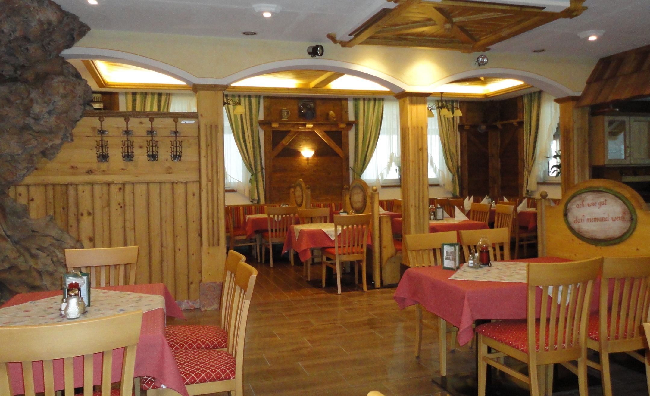 Gemütliches Restaurant mit Holzmöbeln und roten Tischdecken.