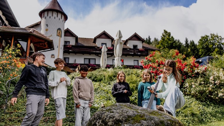 Kinder spielen vor einem Hotel mit einem Schwert in einem Stein.