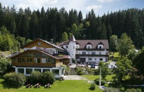 Ein Hotel im Wald mit einem Turm und Garten.