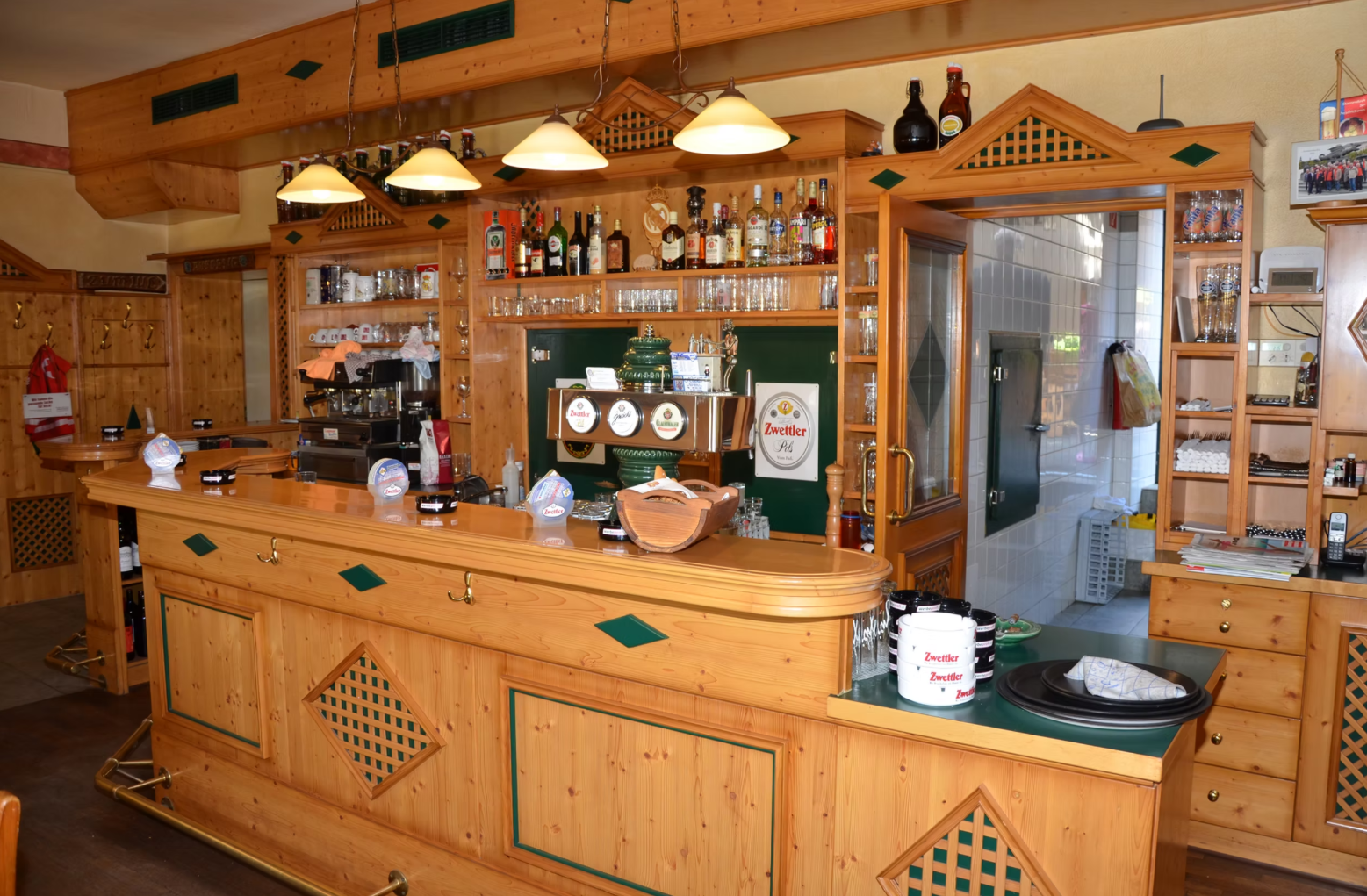 Innenansicht einer rustikalen Bar mit Holzmöbeln und Getränken.