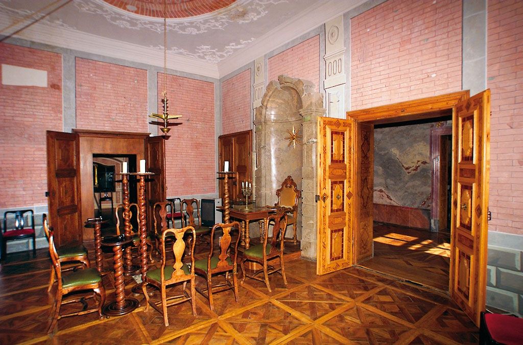 Innenraum des Freimaurermuseums Schloss Rosenau mit Holzmöbeln und dekorativen Wänden.