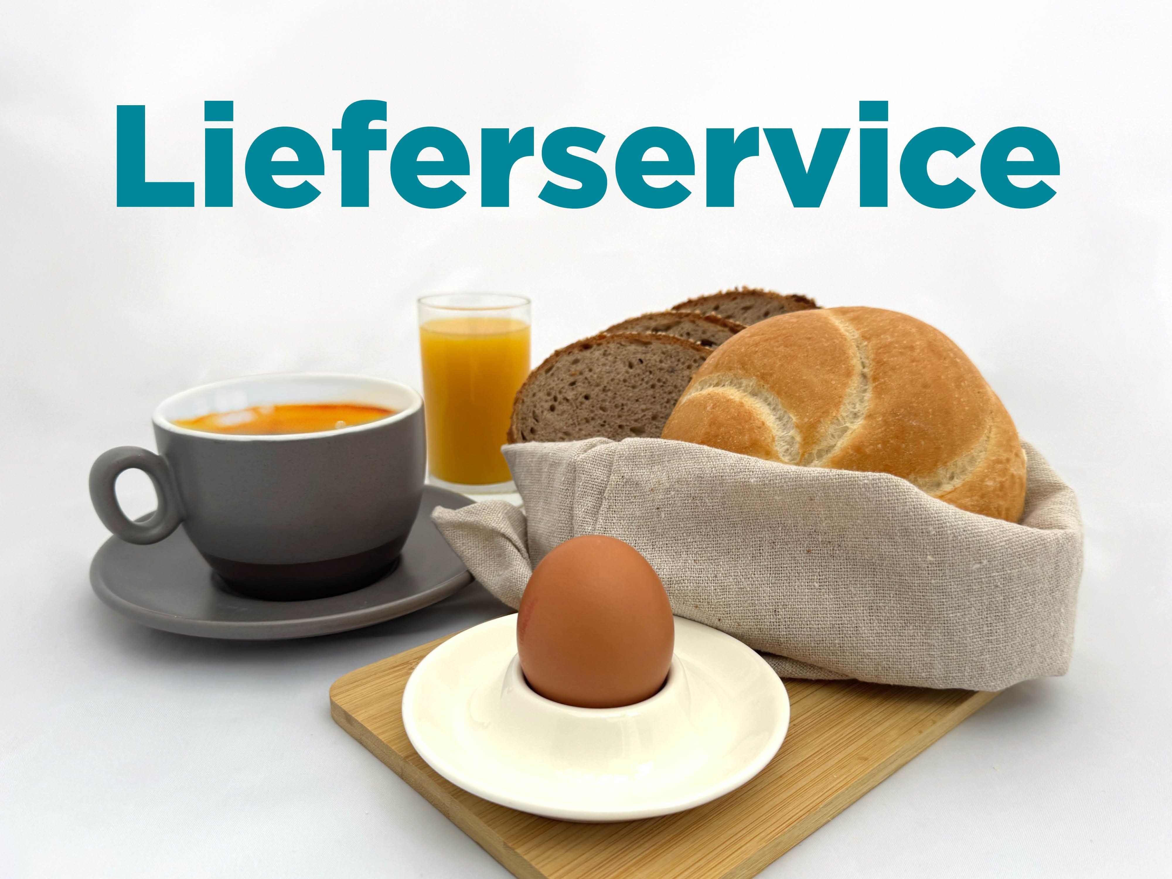 Frühstück mit Brötchen, Ei, Kaffee und Orangensaft auf einem Tisch.