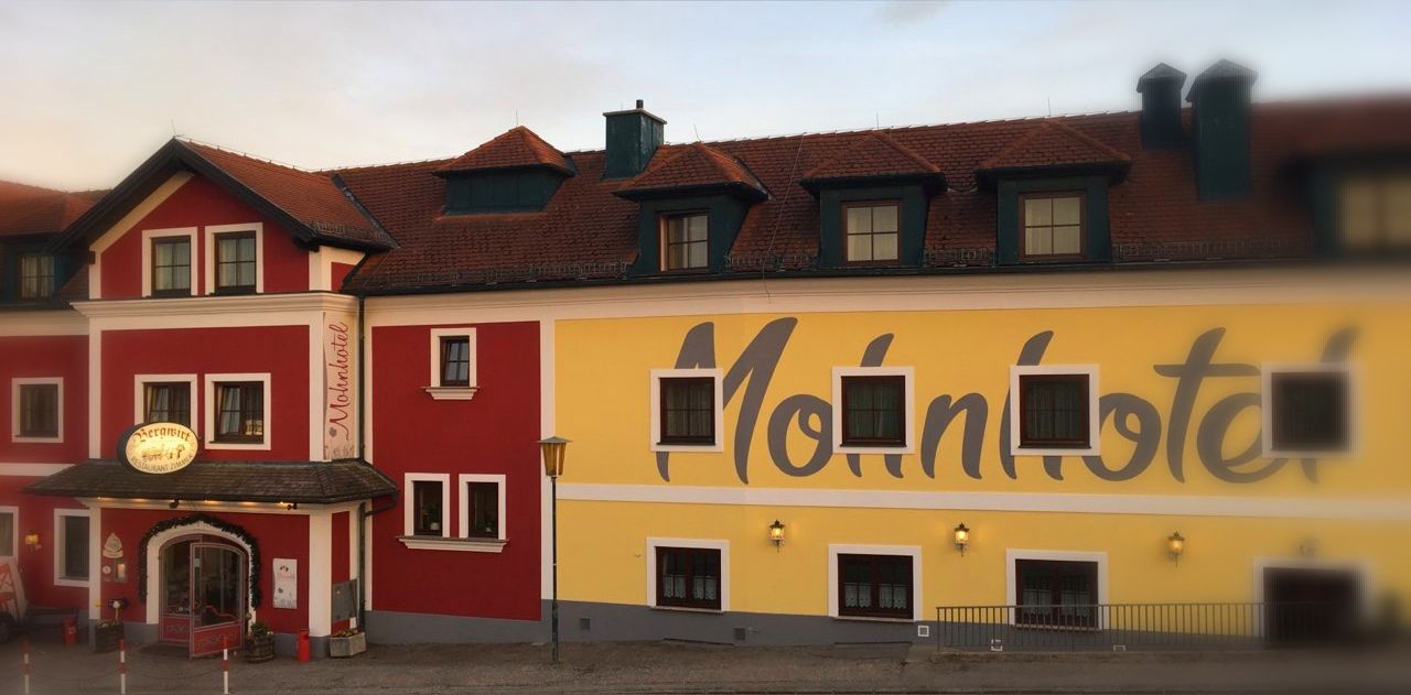 Fassade des Bergwirt Schrammel & Mohnhotel mit rotem und gelbem Anstrich.