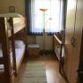 Kinderzimmer mit Etagenbett, Kinderbett, Schrank und Stehlampe.