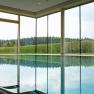 Innenpool mit gro&szlig;en Fenstern und Blick auf Wald und Hecken.