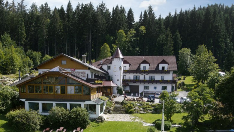 Ein Hotel im Wald mit einem Turm und Garten.
