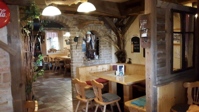 Gemütlicher Innenraum eines rustikalen Pubs mit Holzmöbeln und Backsteinwänden.