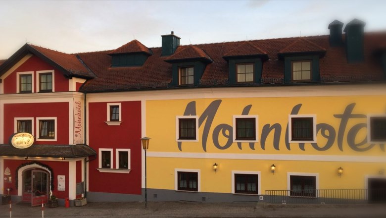 Fassade des Bergwirt Schrammel & Mohnhotel mit rotem und gelbem Anstrich.