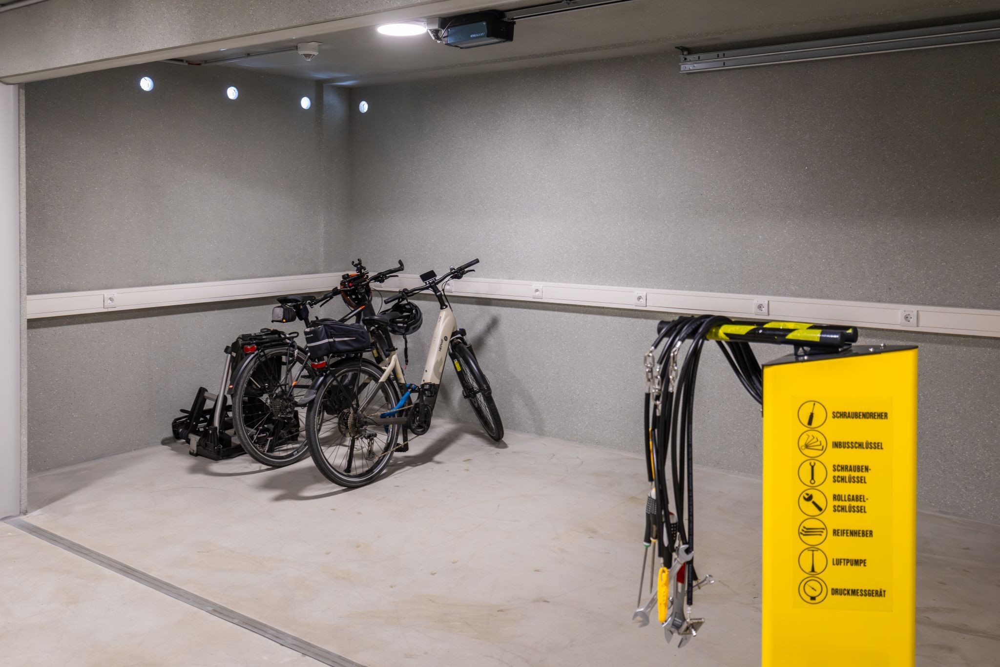 Fahrradabstellraum mit zwei Fahrrädern und einer gelben Werkzeugstation.
