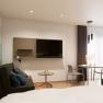 Modern eingerichtetes Apartment mit Sofa, Tisch, St&uuml;hlen und Fernseher.