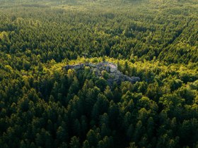 Aussichtsplattform auf einer Felsformation mit Blick &uuml;ber dicht bewaldete H&uuml;gel im Waldviertel aus der Vogelperspektive.