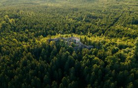 Aussichtsplattform auf einer Felsformation mit Blick &uuml;ber dicht bewaldete H&uuml;gel im Waldviertel aus der Vogelperspektive.