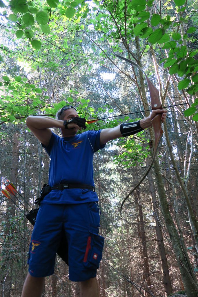 Ein Bogenschütze zielt mit einem Bogen im Wald.