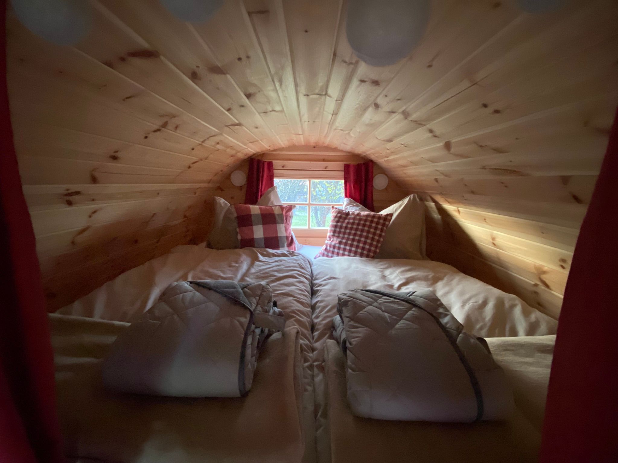 Innenansicht eines gemütlichen Holzschlafzimmers mit Doppelbett und Thermobademänteln.