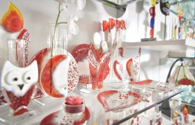 Glasdekorationen in Rot und Wei&szlig; auf einem Regal.