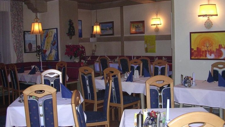 Ein gem&uuml;tliches Restaurant mit Holzm&ouml;beln, gedeckten Tischen und Wanddekorationen.
