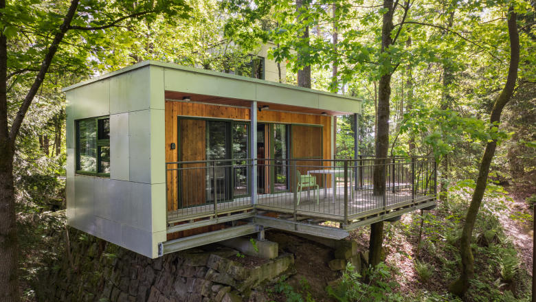 Modernes Baumhaus mit Terrasse im Wald.