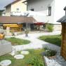 Garten mit Steinen, Holzhaus, Tisch, H&auml;ngematte und Sonnenschirm.