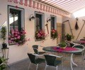 Gem&uuml;tlicher Au&szlig;enbereich eines Gasthauses mit Tischen, St&uuml;hlen und Blumen.