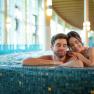 Ein Paar entspannt sich in einem Whirlpool in einem modernen Spa mit gro&szlig;en Fenstern.