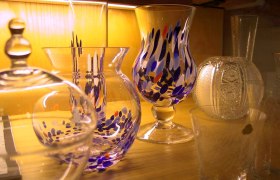 Verschiedene bunte Glasvasen auf einem Holzregal.