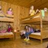 Kinder spielen in einem Zimmer mit Holzstockbetten.