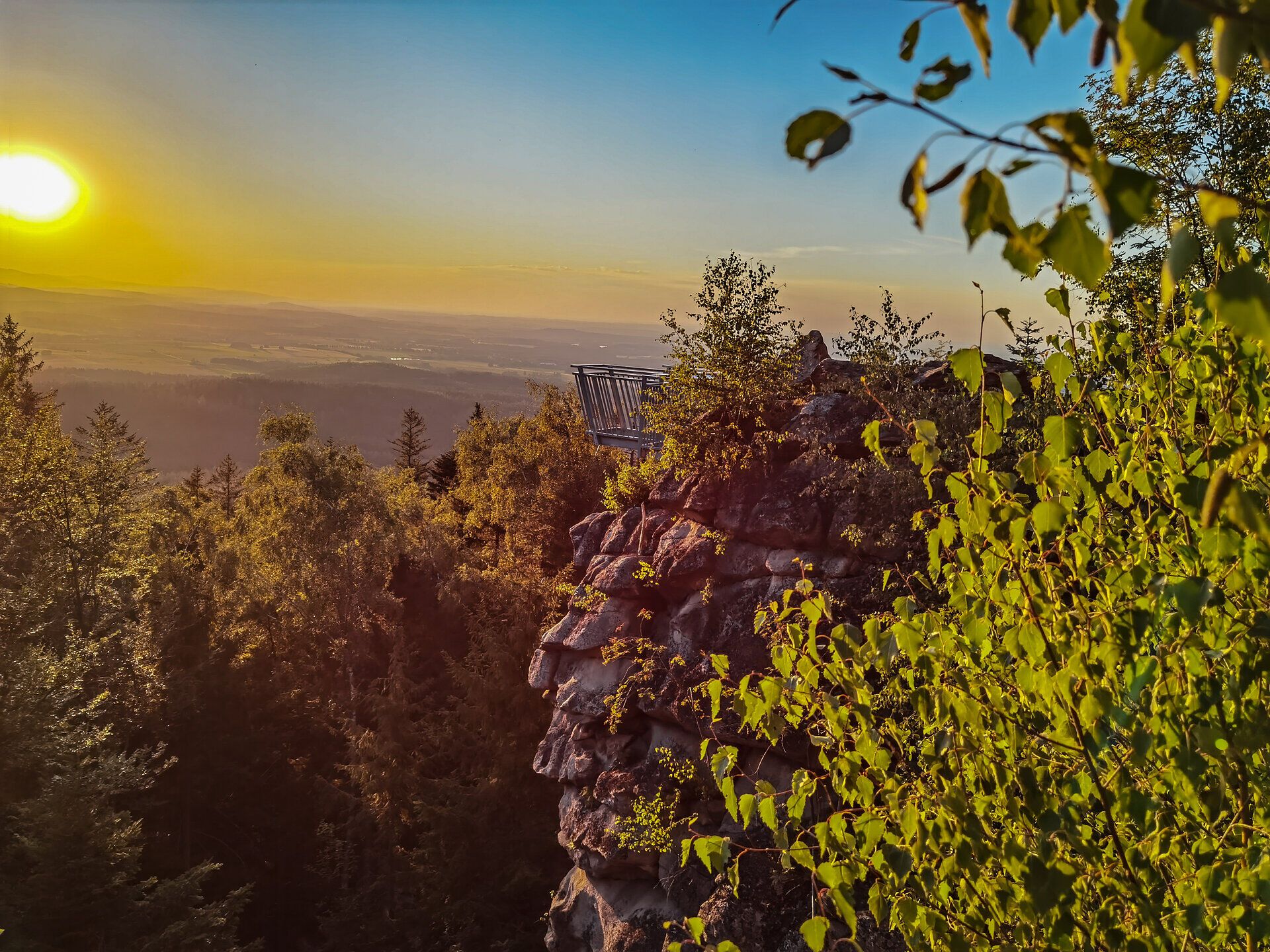 Die goldenen Strahlen der Abendsonne tauchen die Landschaft in ein warmes Licht und verleihen den sanften Hügeln eine magische Atmosphäre. Umgeben von üppigem Grün und dem sanften Rascheln der Blätter, lädt dieser Ort zum Verweilen und Träumen ein.