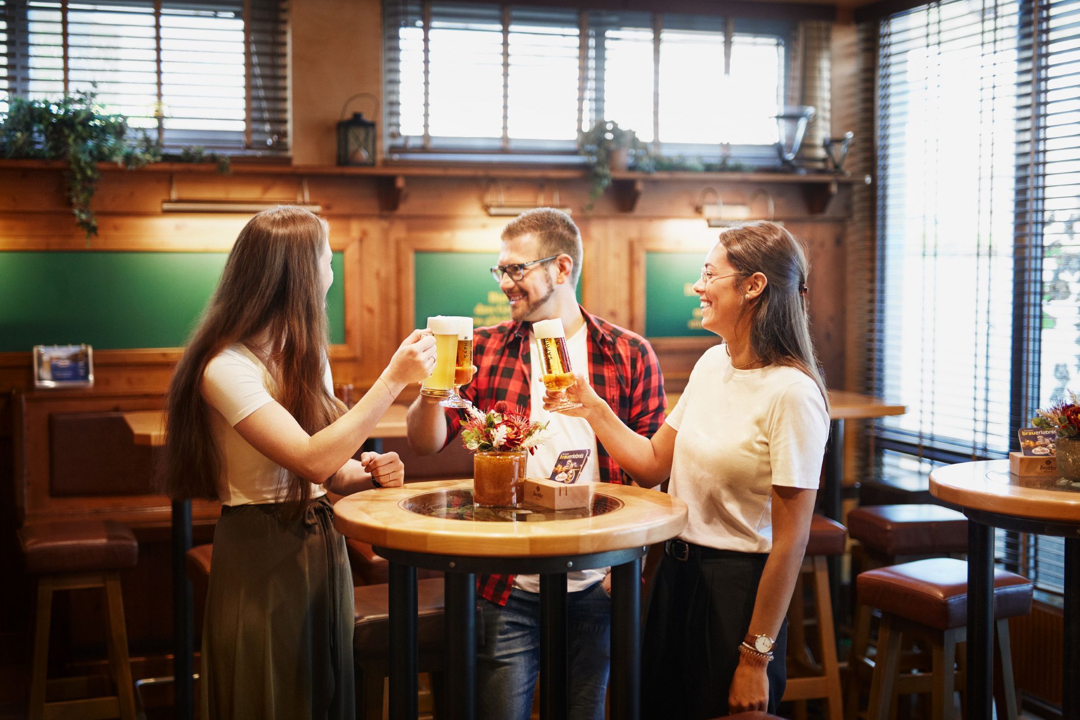 Drei Personen stoßen mit Biergläsern in der Zwickel-Stube an.