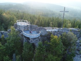 Der Aussichtspunkt auf dem Nebelstein bietet einen atemberaubenden Blick &uuml;ber die umliegenden W&auml;lder und Berge. Die frische, klare Luft und das sanfte Licht der Abendd&auml;mmerung schaffen eine magische Atmosph&auml;re, die zum Verweilen einl&auml;dt. Hier k&ouml;nnen Besucher die Sch&ouml;nheit der Natur in vollen Z&uuml;gen genie&szlig;en.