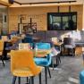 Innenansicht eines modernen Caf&eacute;s mit bunten Samtst&uuml;hlen und Holzw&auml;nden.